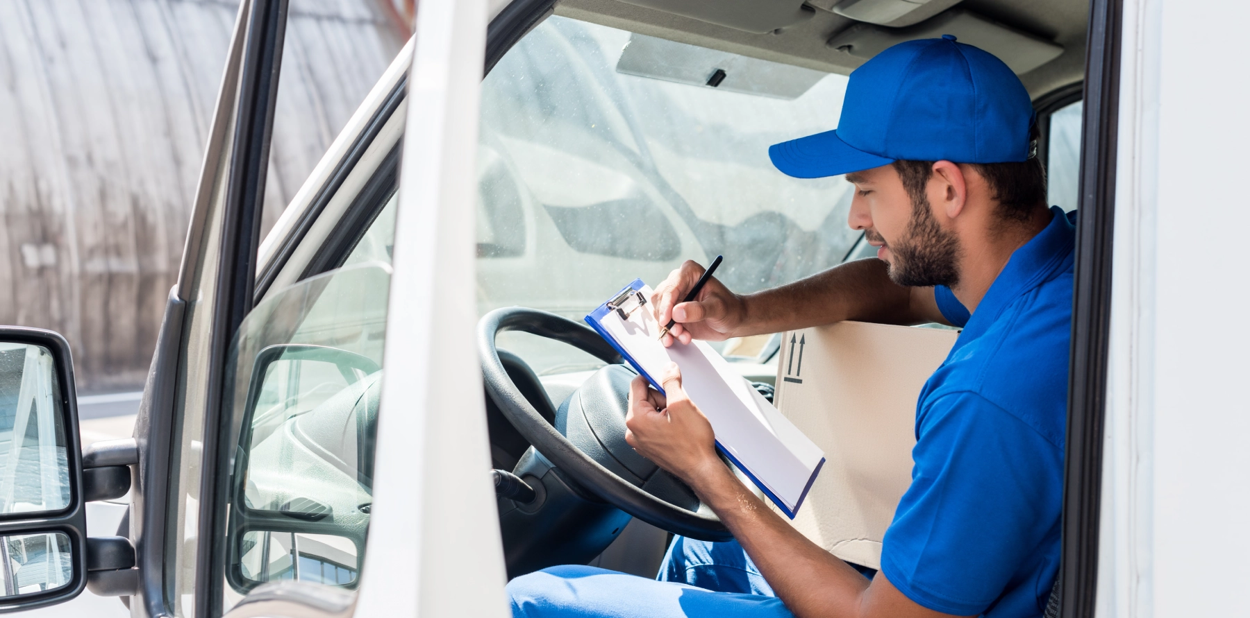 postal service worker in his vehicle signing paperwork